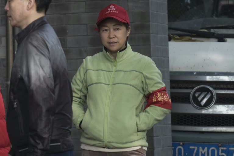 A red-armbanded volunteer for security procedure keeps an eye out for trouble along the road during the Communist Party's 19th Congress in Beijing