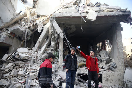 A boy takes a selfie at a damaged site after an airstrike in the besieged town of Douma, Eastern Ghouta, Damascus, Syria February 9, 2018. REUTERS/Bassam Khabieh