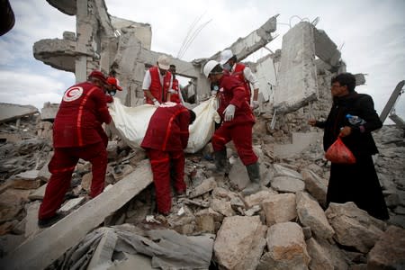 Red Crescent medics carry a body of the victim of Saudi-led airstrikes on a Houthi detention centre in Dhamar