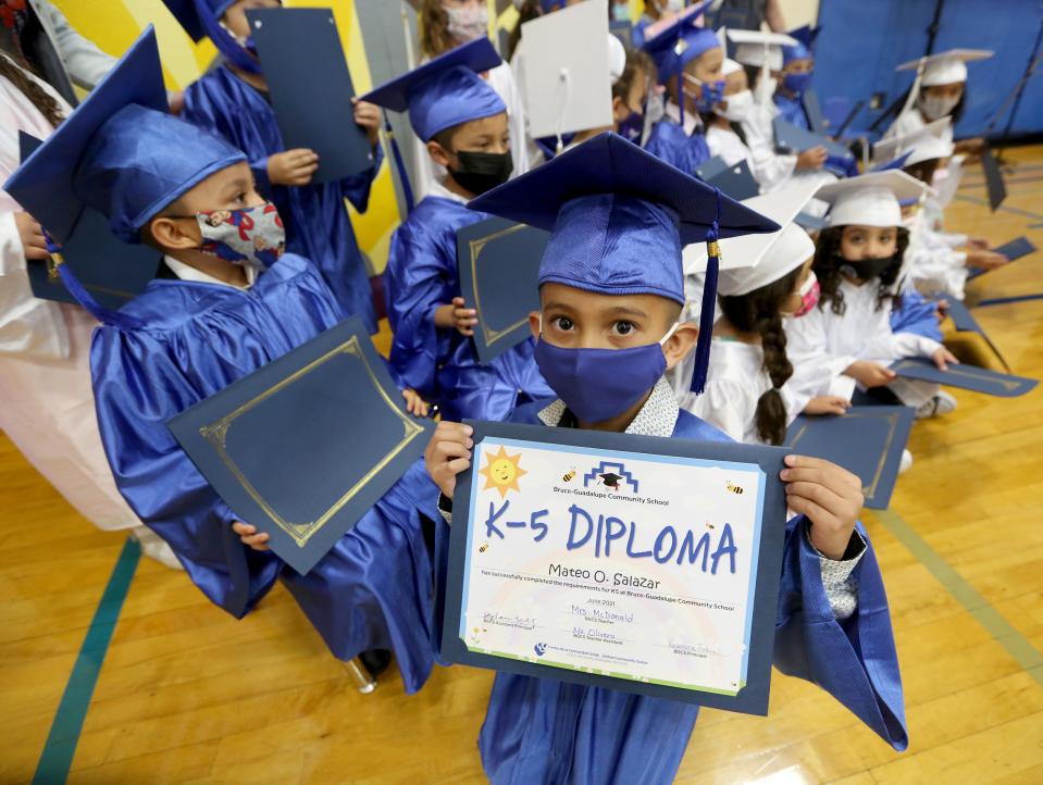 Mateo Salazar holds up his diploma after receiving it during a 5-year-old kindergarten graduation ceremony at Bruce Guadalupe Community School on South 9th Street in Milwaukee on Thursday.