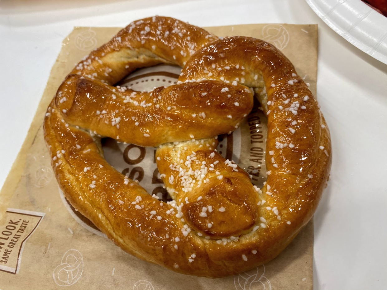 A pretzel at Sam's Club cafe, on a brown pretzel serving bag, on a white table