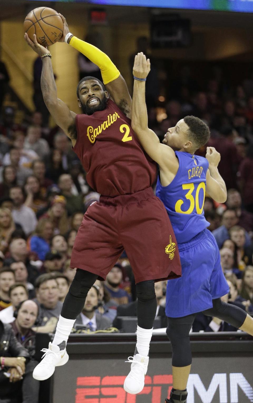Cleveland Cavaliers' Kyrie Irving (2) passes over Golden State Warriors' Stephen Curry (30) in the first half of an NBA basketball game, Sunday, Dec. 25, 2016, in Cleveland. (AP Photo/Tony Dejak)
