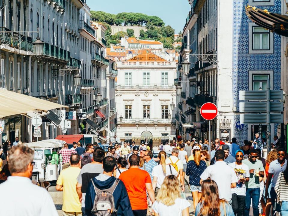 People walk through a bustling street in Lisbon, Portugal.