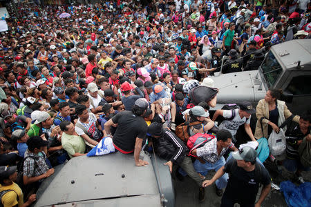 Honduran migrants, part of a caravan trying to reach the U.S., storm a border checkpoint to cross into Mexico, in Tecun Uman, Guatemala October 19, 2018. REUTERS/Ueslei Marcelino