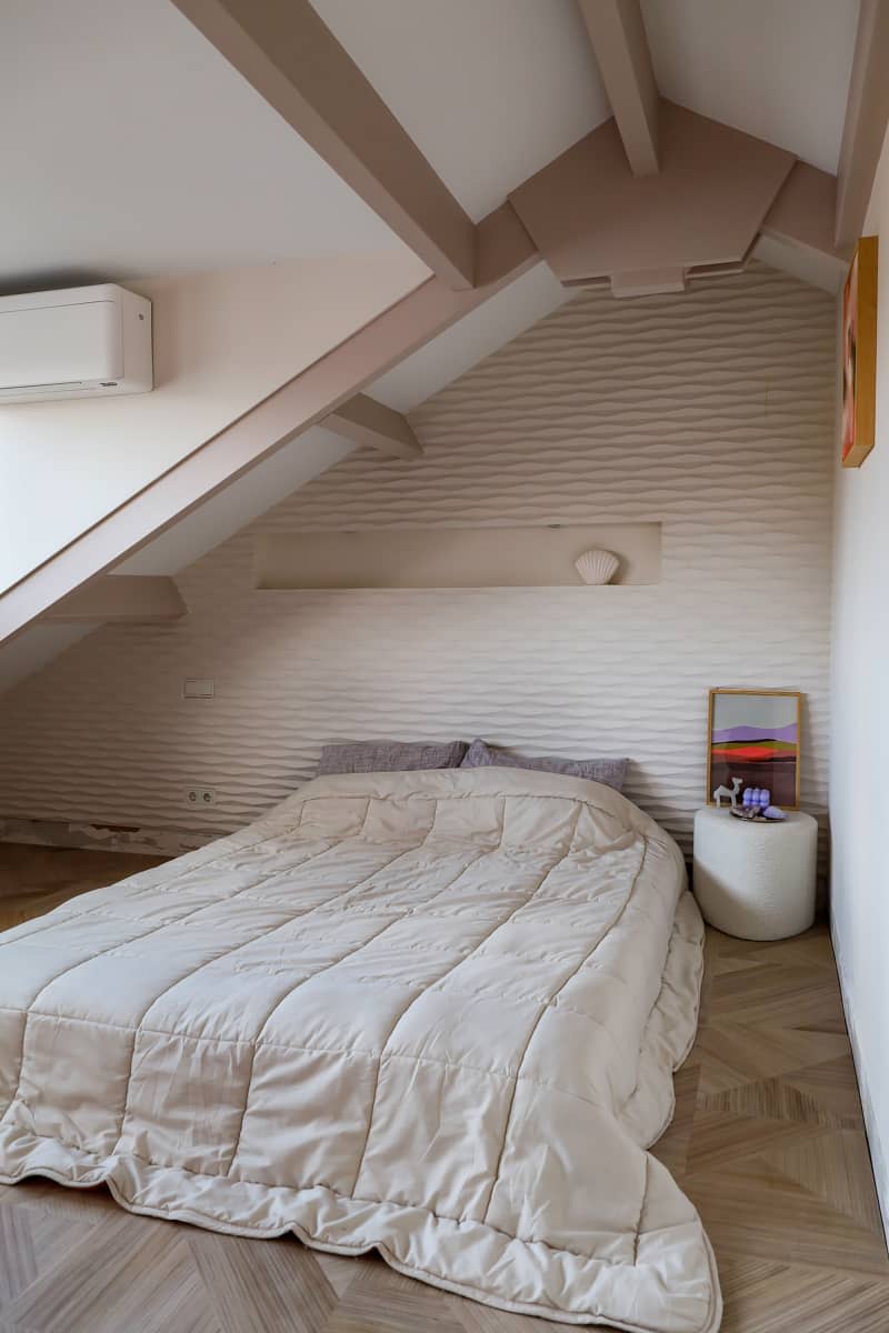 Bed placed under vaulted ceiling in neutral bedroom.