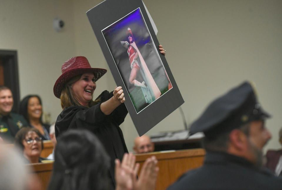 Judge Nicole Menz waves a photo of Leatha Mullins around the courtroom during a comedy presentation of Mullins before her swearing in during the Investiture Ceremony for Mullins at the St. Lucie County Courthouse on Friday, Feb.24, 2023, in Fort Pierce.