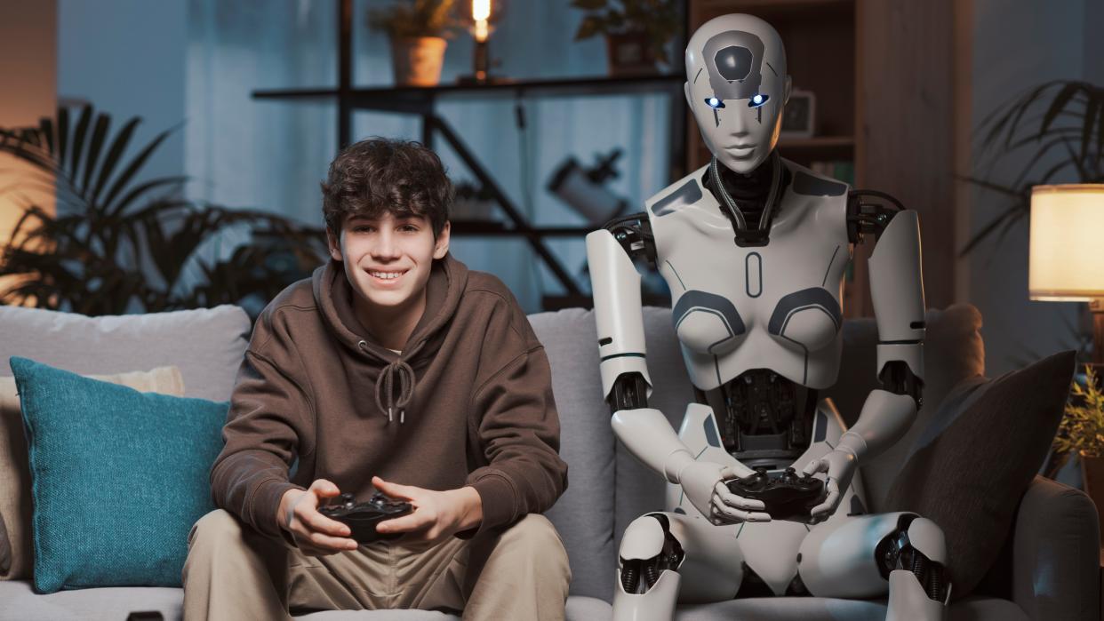  A teenage boy playing games on his couch with a humanoid android beside him. 