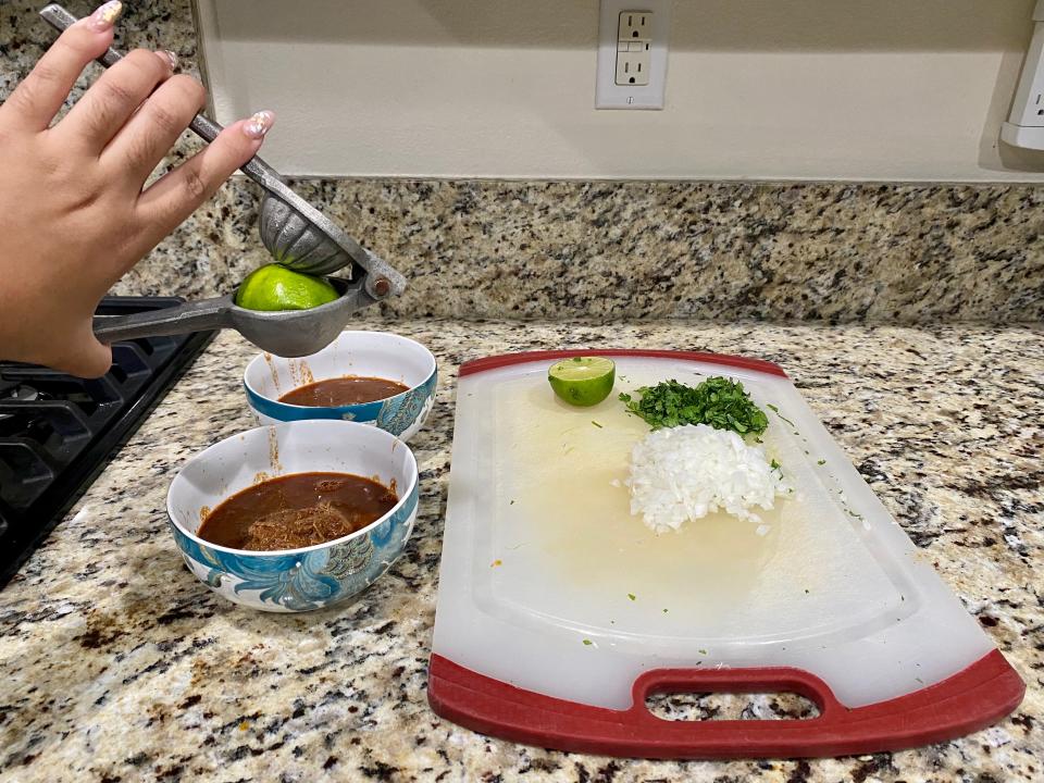 Squeezing lime into a bowl of birria.