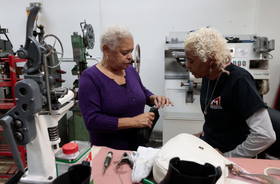 Claudia Helton, 67, left, and her sister Ronda Morrison of the House of Morrison Shoe Repair on Livernois in Detroit talk about the work that needs to be done to a wallet purse for a customer at her store on the Avenue of Fashion on Saturday, Nov. 18, 2023.