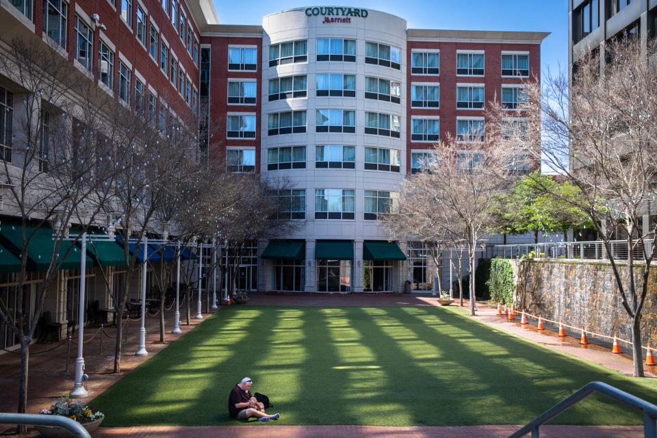 A man sits on the turf lawn in the courtyard off of Main Street, Friday, April 3, 2020.