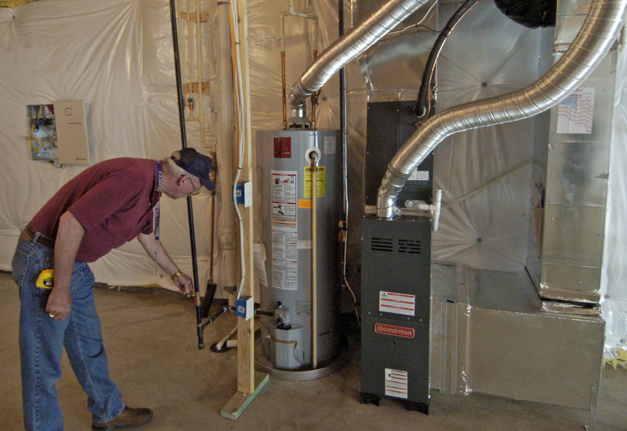 Larry Vanay bends down to inspect a new gas furnace.