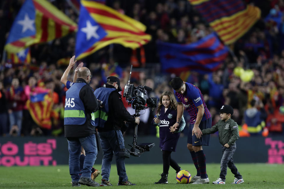 Barcelona forward Luis Suarez walks off the pitch with his children end of the Spanish La Liga soccer match between FC Barcelona and Real Madrid at the Camp Nou stadium in Barcelona, Spain, Sunday, Oct. 28, 2018. (AP Photo/Manu Fernandez)