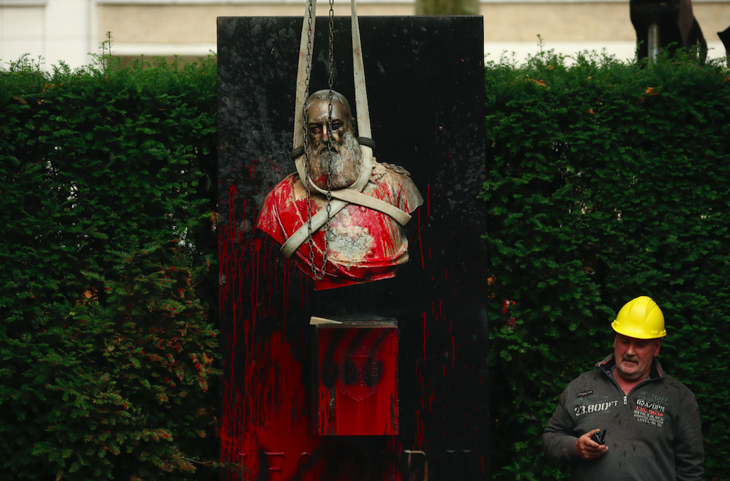 A workman stands by as a bust of Belgium's King Leopold II is hoisted off of its plinth and removed from a park in Ghent, Belgium. (PA)