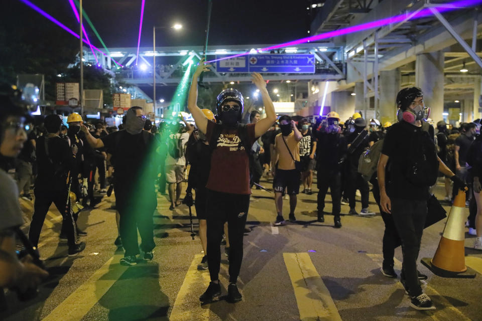 Demonstrators shine laser pointers outside the Yuen Long MTR station during a protest in Hong Kong, Wednesday, Aug. 21, 2019. Hong Kong riot police faced off briefly with protesters occupying a suburban train station Wednesday evening following a commemoration of a violent attack there by masked assailants on supporters of the anti-government movement. (AP Photo/Kin Cheung)