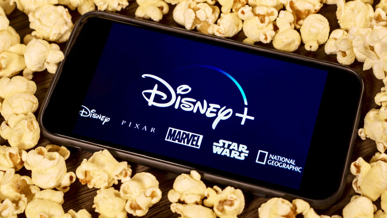  The Disney Plus logo on a phone surrounded by popcorn. 