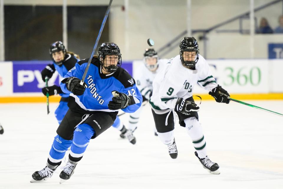 Toronto's Allie Munroe (12) and Boston's Sophie Shirley (9) look for a loose puck during first period PWHL hockey action in Toronto on Wednesday, Jan. 17, 2024. 