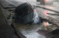 <p>A car is seen in a sinkhole on Frederick Avenue near North Bend Road in Baltimore, Md., during Sunday’s storm on May 27, 2018. (Photo: Jerry Jackson/Baltimore Sun/TNS via Getty Images) </p>