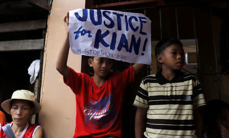 A school boy holds up a placard at the wake of Kian Loyd delos Santos, a 17-year-old high school student, who was among the people shot dead last week in an escalation of President Rodrigo Duterte's war on drugs in Caloocan city, Metro Manila, Philippines August 21, 2017. REUTERS/Erik De Castro