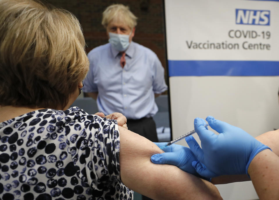 FILE - In this Tuesday, Dec. 8, 2020 file photo, British Prime Minister Boris Johnson watches as nurse Rebecca Cathersides administers the Pfizer-BioNTech COVID-19 vaccine to Lyn Wheeler at Guy's Hospital in London. Britain is racing to vaccinate more than 15 million people by mid-February, and in an effort to ensure vaccines get to the right places at the right times, along with the syringes, alcohol swabs and protective equipment needed to administer them, the government has called in the army. (AP Photo/Frank Augstein, Pool, File)