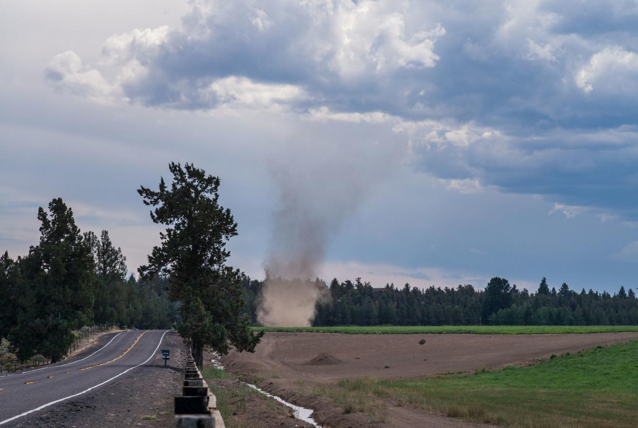 A dust devil is spinning up dust on a country farm.