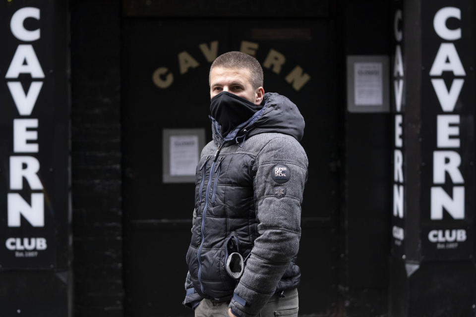 A member of the entertainment industry stands outside the Cavern Club in Liverpool, England, Monday Oct. 12, 2020, during a show of support for the hard hit sector as Prime Minister Boris Johnson lays out a new three-tier alert system for England. The British government is set to announce new restrictions on business and socializing in major northern England cities with high infection rates, under a plan to put areas into three tiers. (AP Photo/Jon Super)