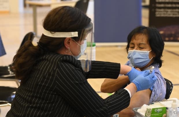 Tamara Dus, left, administers a first COVID-19 vaccine to personal support worker Anita Quidangen at a hospital in Toronto on Dec. 14, 2020. (Frank Gunn/The Canadian Press - image credit)