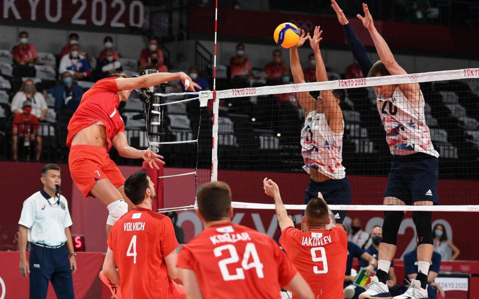 Russia's Dmitry Volkov (L) spikes the ball in the men's preliminary round pool B volleyball match between USA and Russia - AFP