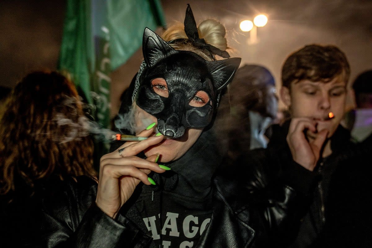 People smoke marijuana cigarettes in front of the Brandenburg Gate (AP)