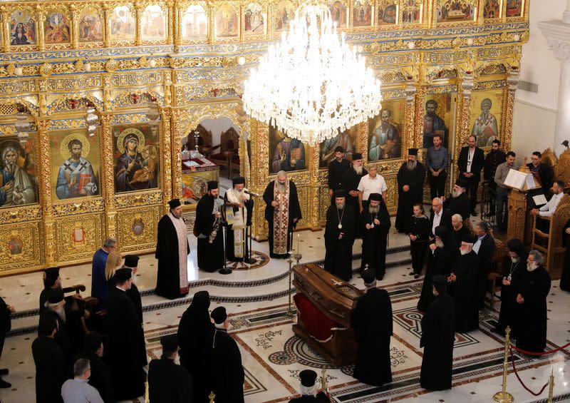 Greek Orthodox priests carry out a liturgy by the coffin of the late Archbishop Chrysostomos II in the Apostle Varnavas Cathedral in Nicosia