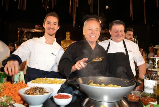 Wolfgang Puck (C) and his son Byron Puck (L) prepare a dish during the Governors Ball press preview in Hollywood on January 31