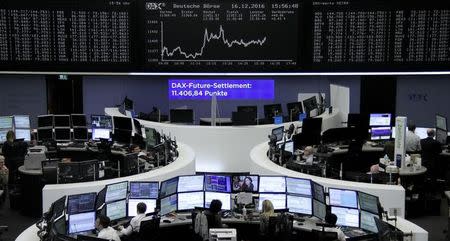 Traders work at their desks in front of the German share price index, DAX board, at the stock exchange in Frankfurt, Germany, December 16, 2016. REUTERS/Staff/Remote