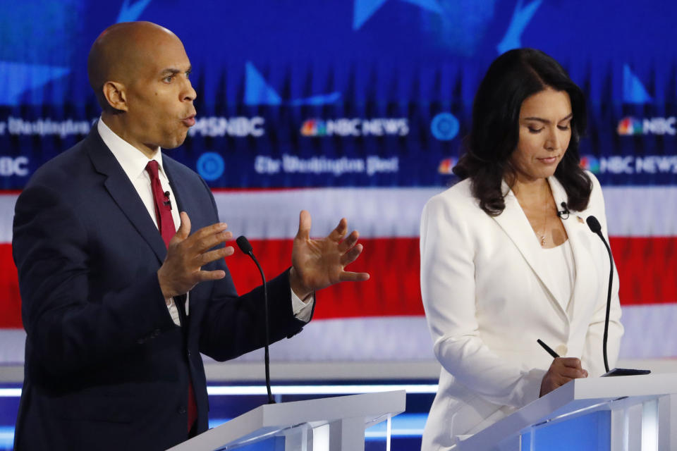 Democratic presidential candidate Sen. Cory Booker, D-N.J., speaks as Democratic presidential candidate Rep. Tulsi Gabbard, D-Hawaii, listens during a Democratic presidential primary debate, Wednesday, Nov. 20, 2019, in Atlanta. (AP Photo/John Bazemore)