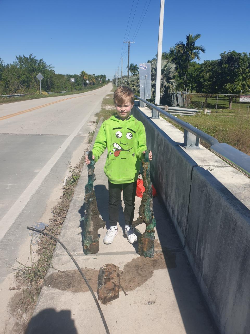 Allen Cadwalader, 11, holds the lower receivers of two .50-caliber sniper rifles he and his grandfather found in a Miami-Dade County canal Sunday, Jan. 30, 2022