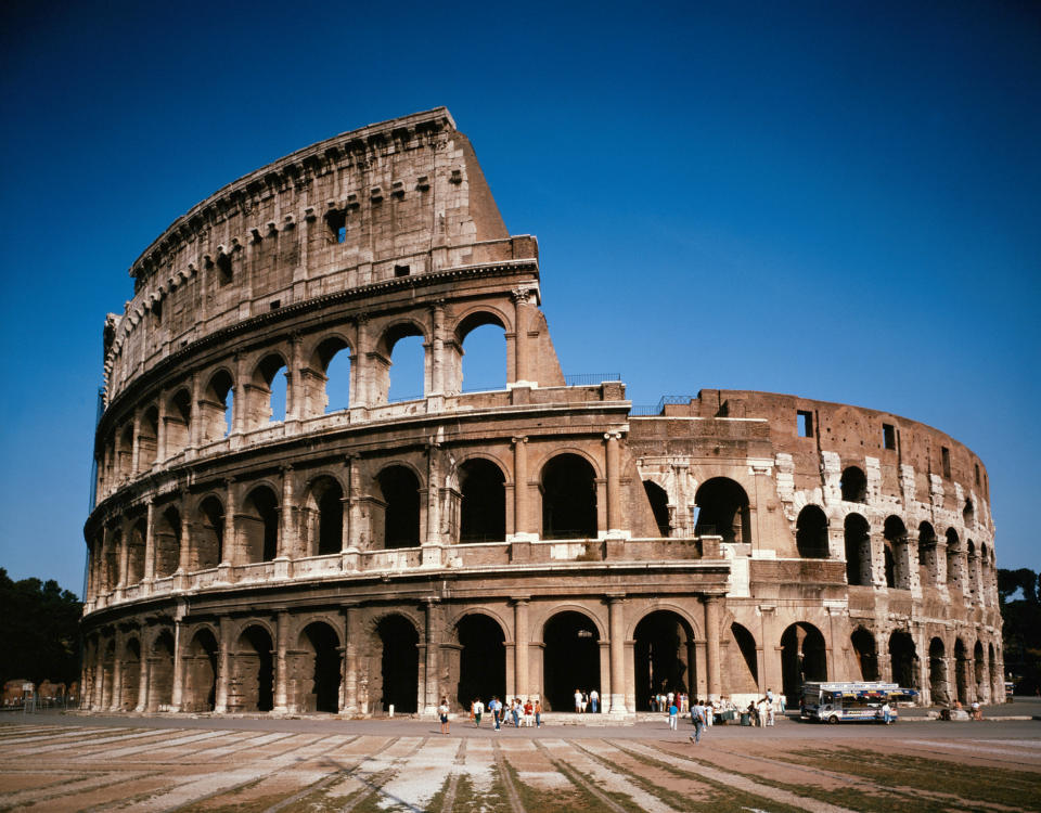 Exterior view of the Colosseum in Rome, showing the ancient structure's arches and partial ruins