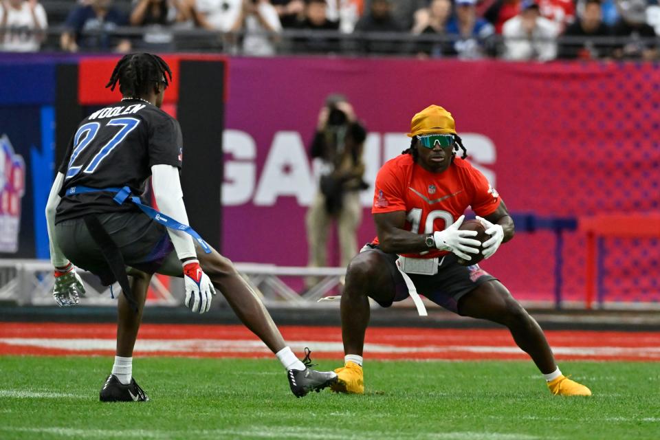 AFC wide receiver Tyreek Hill (10) of the Miami Dolphins runs with the football as NFC cornerback Tariq Woolen (27) of the Seattle Seahawks defends during the flag football event at the NFL Pro Bowl, Sunday, Feb. 5, 2023, in Las Vegas.