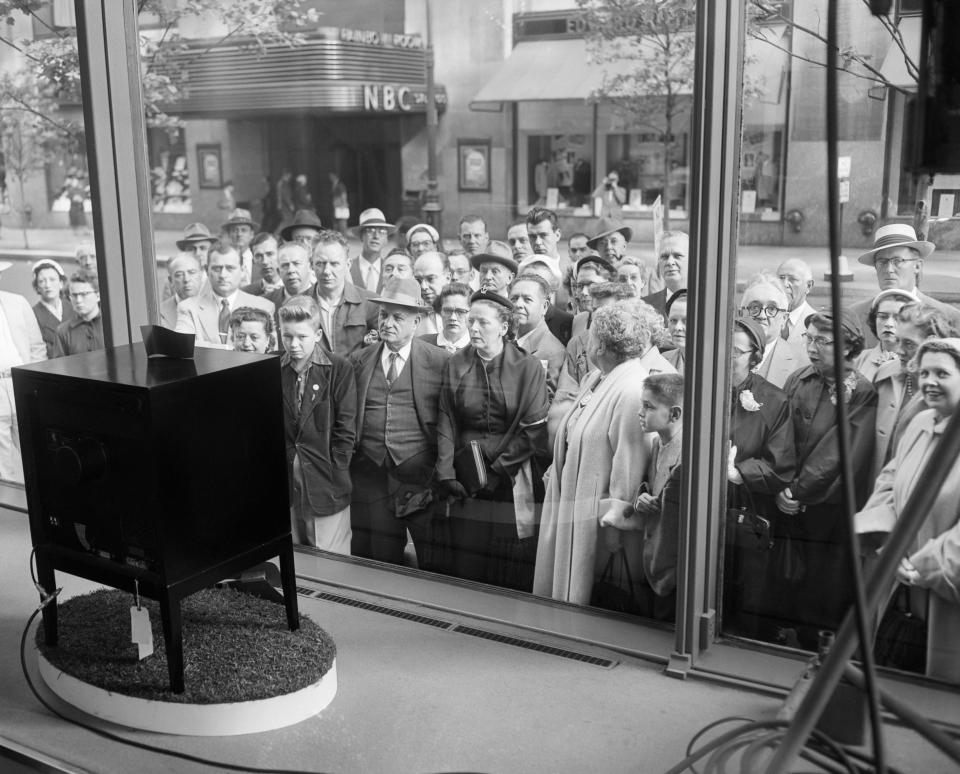 A crowd watching TV through a store window