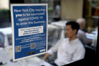 FILE - In this Sept. 13, 2021, file photo, a notice explaining that proof of vaccination is required to dine inside is seen at a restaurant in midtown Manhattan in New York. In both the U.S. and the EU, officials are struggling with the same question: how to boost vaccination rates to the max and end a pandemic that has repeatedly thwarted efforts to control it. In the United States, President Joe Biden has issued sweeping vaccine mandates. (AP Photo/Seth Wenig, File)