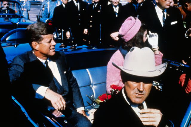 <p>Getty</p> President John F. Kennedy rides in a motorcade through downtown Dallas before he was assassinated on November 22, 1963.
