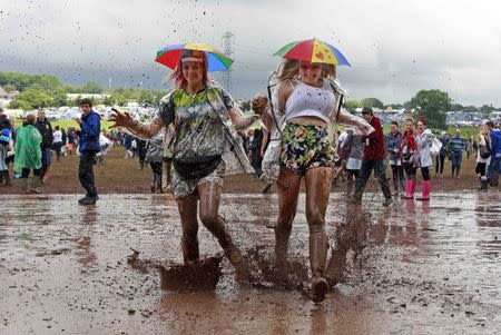 Festival goers splash through a muddy puddle at Worthy Farm in Somerset, on the third day of the Glastonbury music festival June 27, 2014. REUTERS/Cathal McNaughton