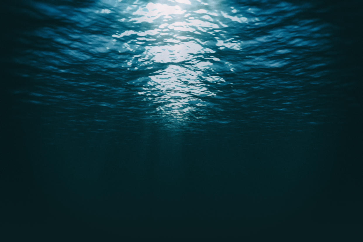 Blue sea with rays of sunlight, ocean surface seen from underwater