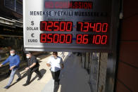 People walk past an exchange office in Istanbul, Friday, Aug. 7, 2020. Turkey's currency tumbled further Friday, hitting another record low. The Turkish lira dropped to 7.3677 against the dollar before making a recovery. The lira is down about 19% versus the U.S. currency since the beginning of the year. (AP Photo/Emrah Gurel)