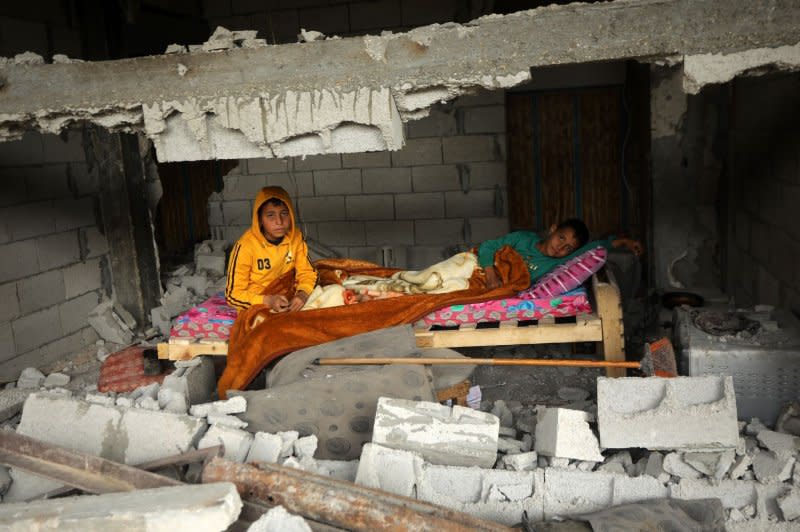 Palestinian boys sit amid the ruins of the family home destroyed in an Israeli strike in Khan Yonis Gaza, on Monday. Photo by Ismail Muhammad/UPI