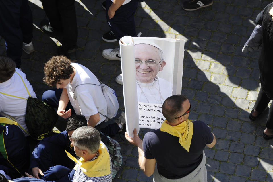 A pilgrim holds a poster of Pope Francis in Piazza della Madonna Square as they wait for him to arrive at the Catholic Shrine of Our Lady of Loreto in central Italy for a one-day visit, Monday, March 25, 2019. The pope chose Loreto to sign the Post-Synodal Exhortation of last October's Synod of Bishops. (AP Photo/Sandro Perozzi)