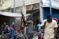 An oof-duty police officer fires his weapons in the air during a protest over police pay and working conditions for the national police, in Port-au-Prince, Haiti, Sunday, Feb. 23, 2020. Off-duty police officers and their supporters exchanged fire for nearly two hours with members of the newly reconstituted Haitian army in front of the national palace. (AP Photo/Dieu Nalio Chery)