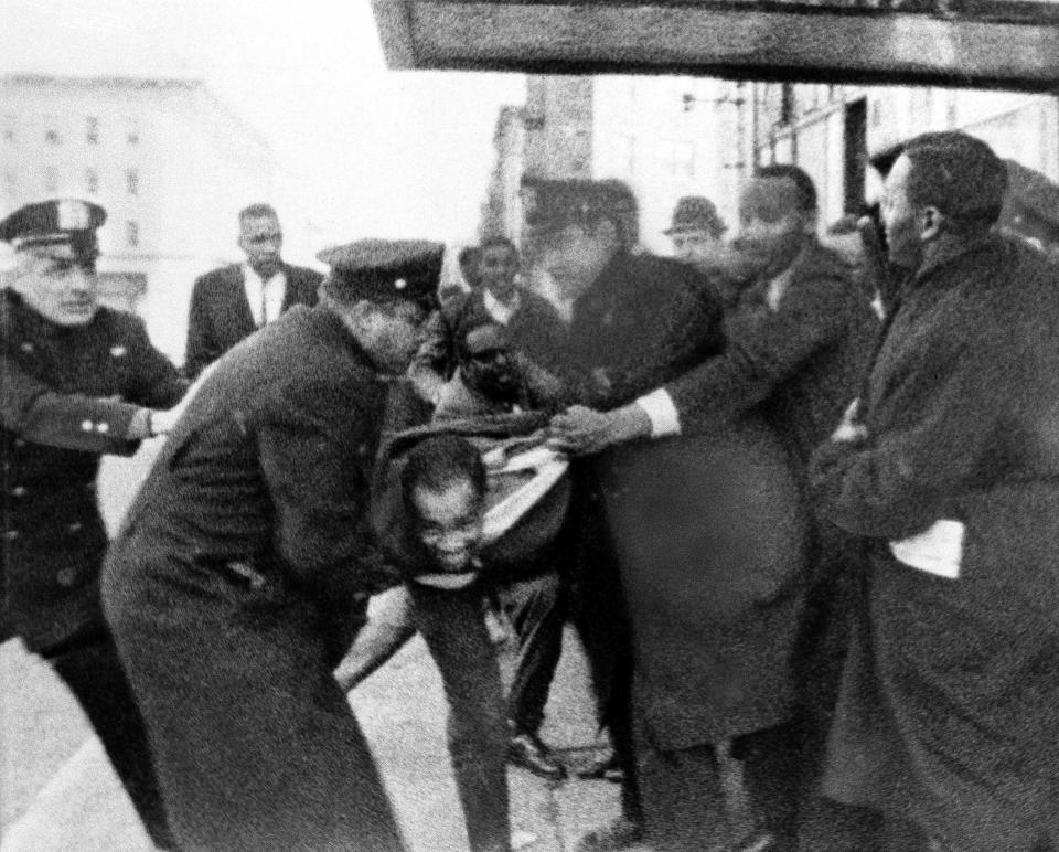 FILE - This photo, released by WCBS-TV, shows Thomas Hagan, 22, struggling with police who take him from the scene outside the ballroom where Malcolm X was shot and killed in New York, Feb. 21,1965. Two men convicted in the assassination of Malcolm X are set to be cleared after more than half a century, with prosecutors now saying authorities withheld evidence in the civil rights leader's killing, according to a news report Wednesday, Nov. 17, 2021. (AP Photo/WCBS-TV News, File)