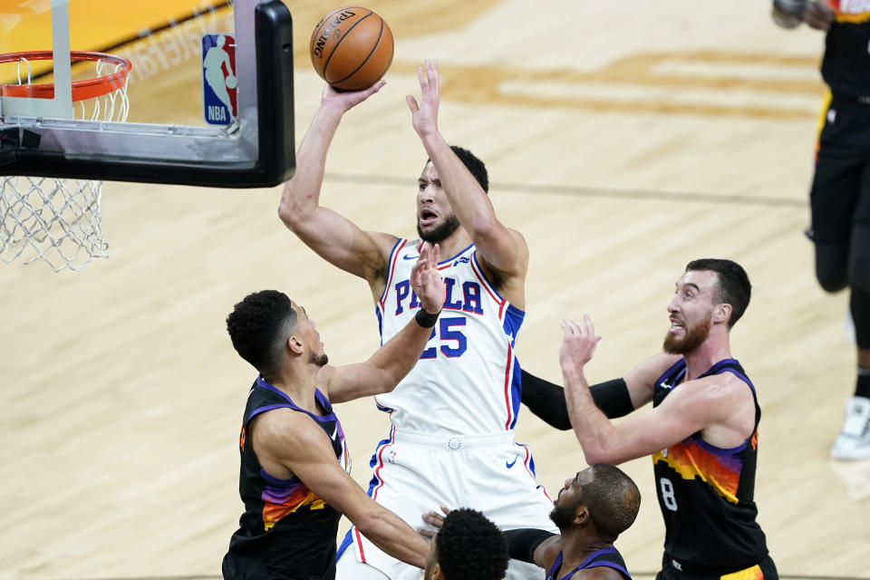 Philadelphia 76ers guard Ben Simmons (25) shoots over Phoenix Suns guard Devin Booker, left, during the first half of an NBA basketball game, Saturday, Feb. 13, 2021, in Phoenix.(AP Photo/Matt York)