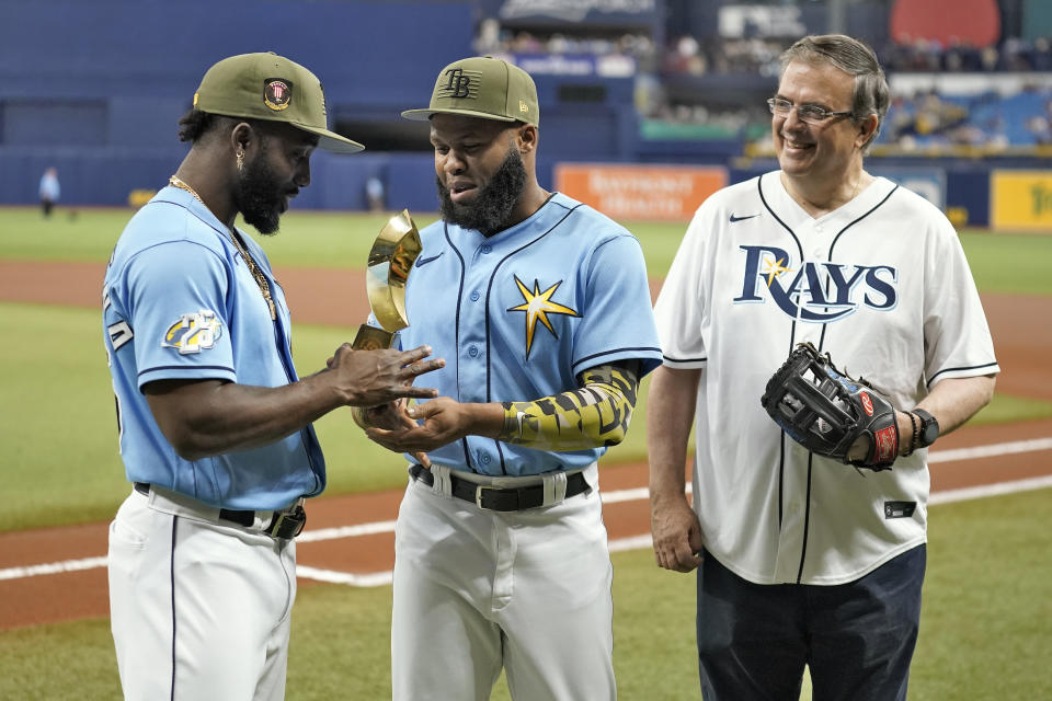 Marcelo Ebrard, right, Mexico's Secretary of Foreign Affairs, looks on as Tampa Bay Rays' Manuel Margot, center, presents Randy Arozarena, left, his 2023 World Baseball Classic All-Tournament Team award, before a baseball game between the Rays and the Milwaukee Brewers Sunday, May 21, 2023, in St. Petersburg, Fla. (AP Photo/Chris O'Meara)