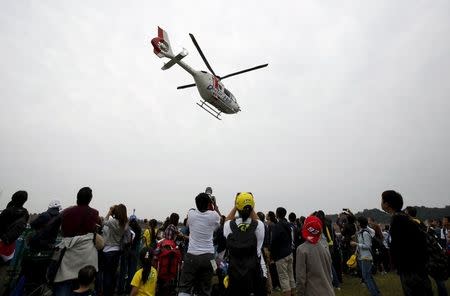 A medical helicopter carrying ART E-Motion Iodaracing Team MotoGP rioder Alex De Angelis of San Marino flies over spectators after Angelis crashed during fourth free practice session for Sunday's Japanese Grand Prix at the Twin Ring Motegi circuit in Motegi, north of Tokyo, Japan, October 10, 2015. REUTERS/Issei Kato