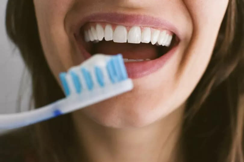 Close up of young woman brushing teeth - stock photo