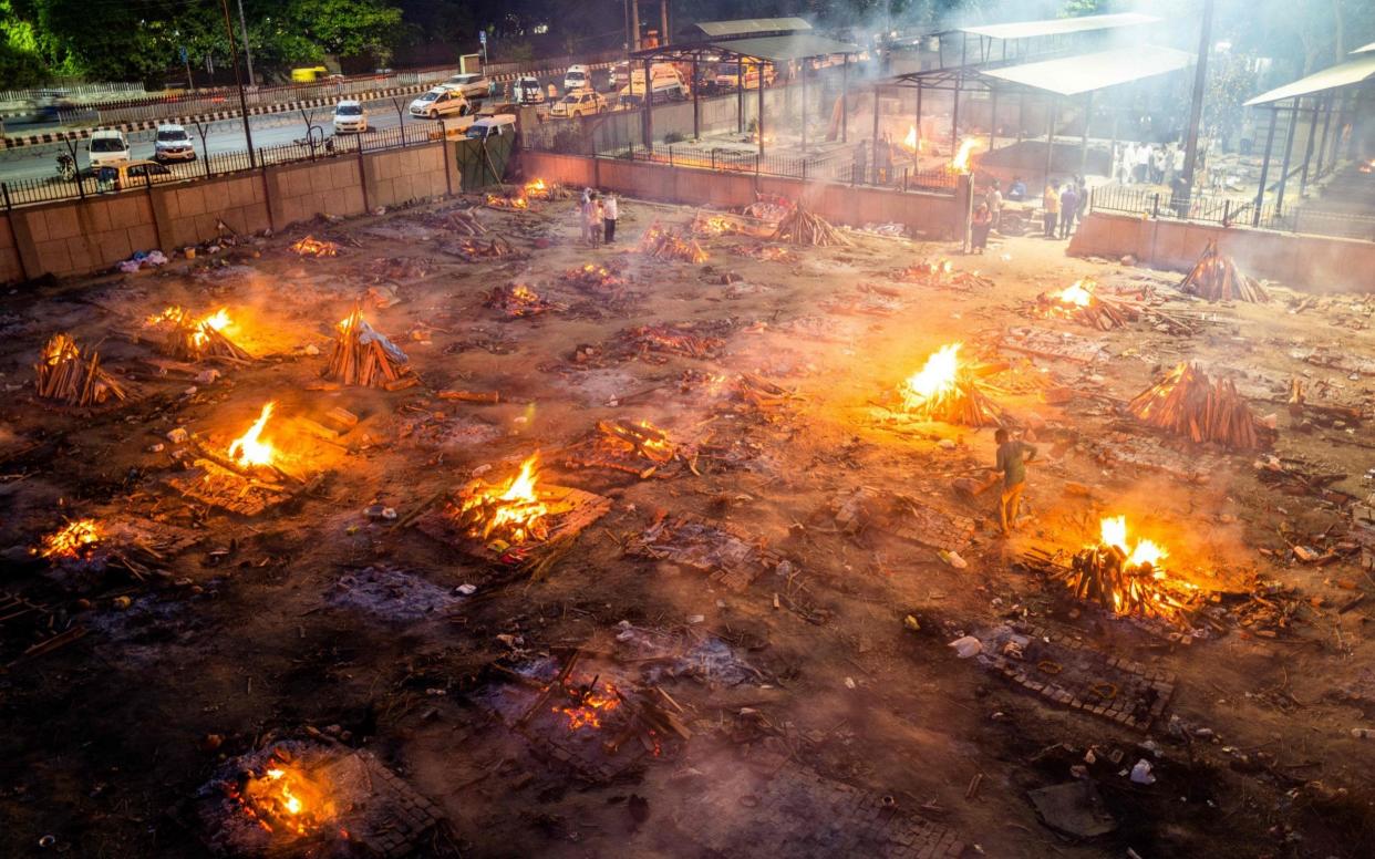 Men are seen around the burning pyres of victims who lost their lives due to the Covid-19 coronavirus at a cremation ground in New Delhi on April 26, 2021.  - JEWEL SAMAD /AFP